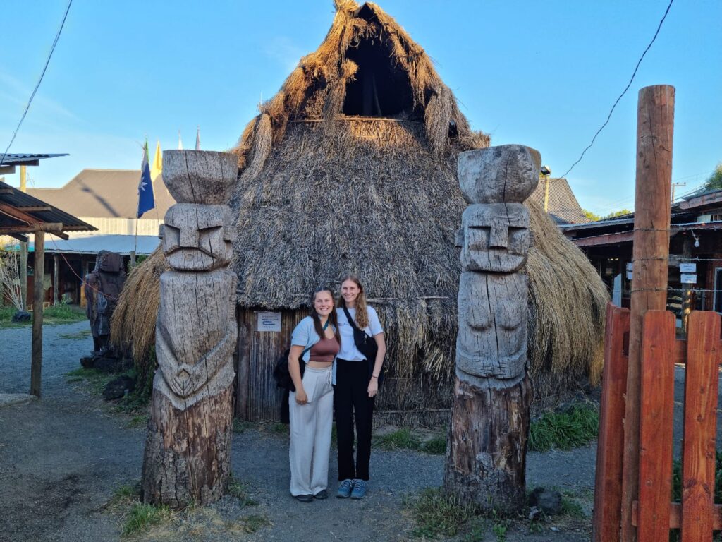 Persönliche Eindrücke aus Pucon: zwei geschnitzte Holz Statuen vor einer traditionellen Ruka, die Strohhäuser der Mapuche