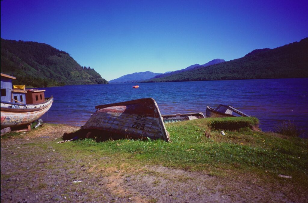Puyuhuapi-Fjord mit Holzbooten am Ufer und blauem Himmel